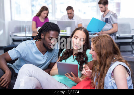 Students using digital tablet with friends in background Stock Photo
