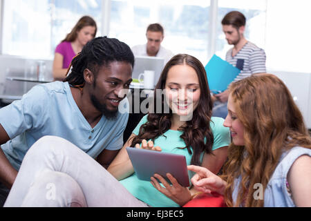 Students using digital tablet with friends in background Stock Photo
