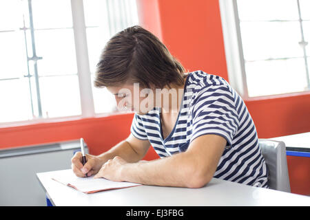 Male student writing notes in classroom Stock Photo