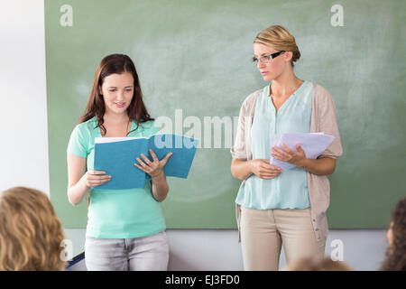 Student explaining notes besides teacher in class Stock Photo