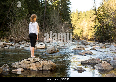 Nine year old girl standing on a boulder gazing upon the Snoqualmie River, near North Bend, Washington, USA Stock Photo