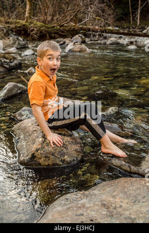 Seven year old boy overacting how cold the water is while dipping his foot into the Snoqualmie River, in North Bend, Washington Stock Photo