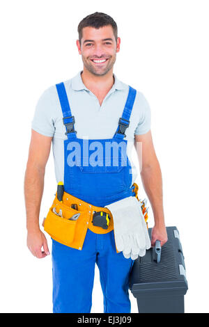 Happy workman in overalls holding toolbox Stock Photo