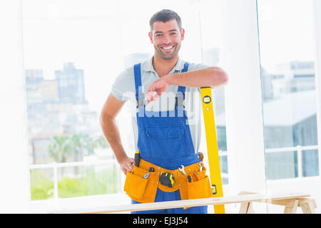 Carpenter in overalls with spirit level in office Stock Photo