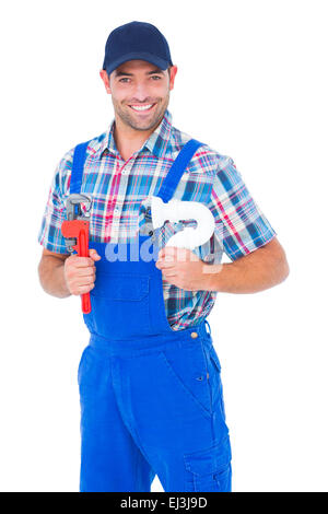 Happy male plumber holding monkey wrench and sink pipe Stock Photo