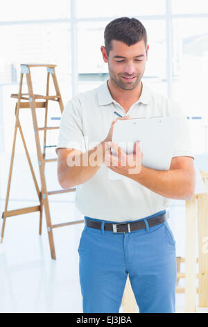 Handyman writing on clipboard at construction site Stock Photo