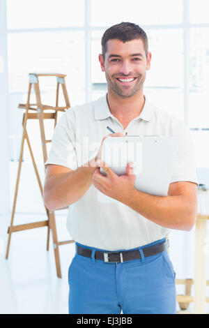 Smiling handyman writing on clipboard at construction site Stock Photo