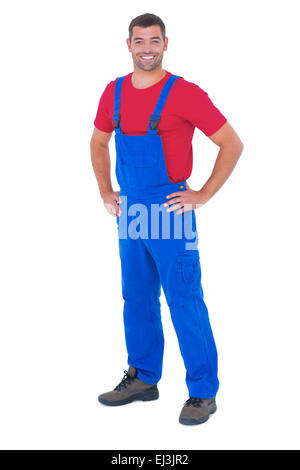 Happy handyman in overalls with hands on hip Stock Photo