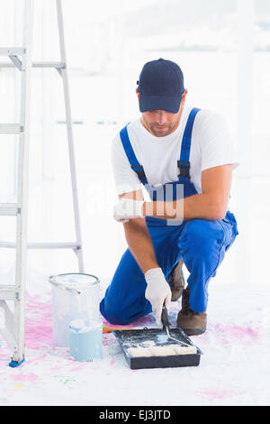 Handyman using paint roller in tray at home Stock Photo