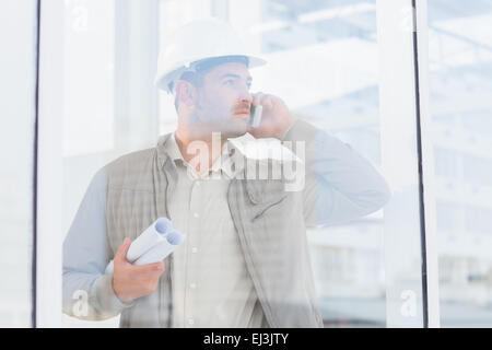 Architect with blueprints using mobile phone in office Stock Photo