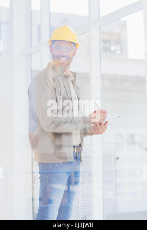 Architect writing on clipboard in office Stock Photo