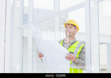Thoughtful architect holding blueprint in office Stock Photo