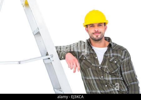 Smiling handyman in overalls leaning on ladder Stock Photo