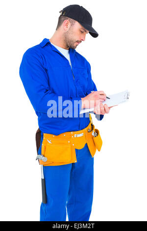 Handyman in blue overall writing on clipboard Stock Photo