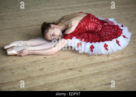 Charming young dancer doing stretching leaned over, looking at t Stock Photo