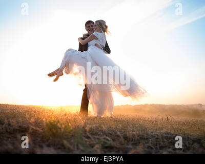 Husband carries his beloved wife in arms Stock Photo