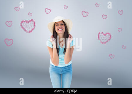 Composite image of happy young brunette wearing sunhat Stock Photo