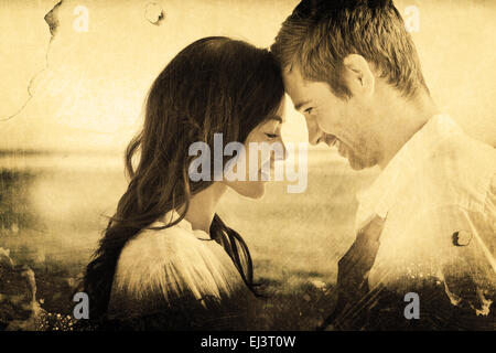 Composite image of romantic couple relaxing and embracing on the beach Stock Photo