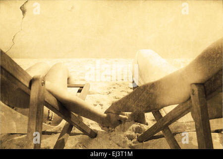 Composite image of couple resting on deck chairs Stock Photo