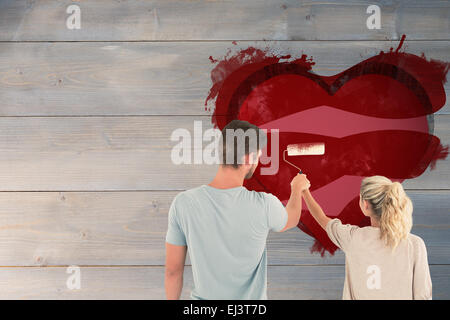 Composite image of young couple painting with roller Stock Photo