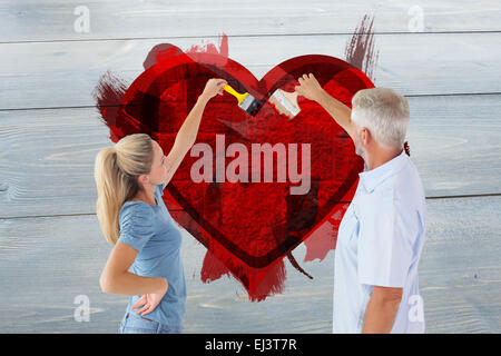 Composite image of happy couple painting wall with paintbrushes Stock Photo