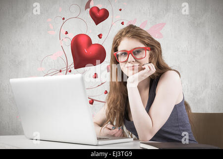 Composite image of pretty redhead working on laptop Stock Photo