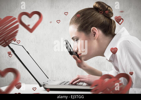 Composite image of businesswoman typing and looking through magnifying glass Stock Photo