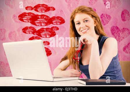 Composite image of pretty redhead working on laptop Stock Photo