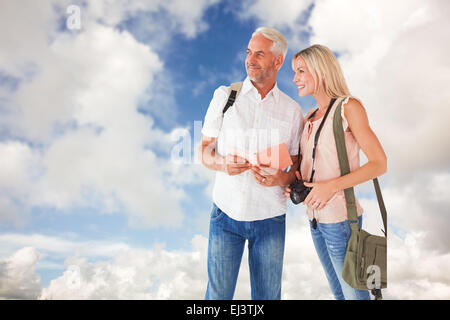 Composite image of happy tourist couple using the guidebook Stock Photo