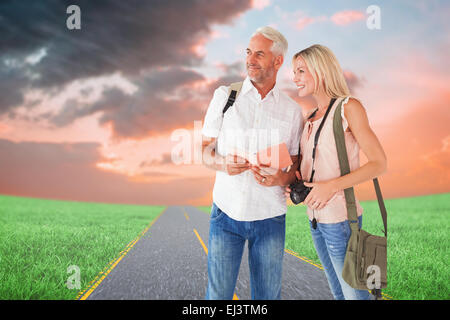Composite image of happy tourist couple using the guidebook Stock Photo