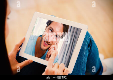 Composite image of handsome smiling man sitting on bed looking at camera Stock Photo