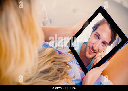 Composite image of handsome smiling man sitting on bed looking at camera Stock Photo