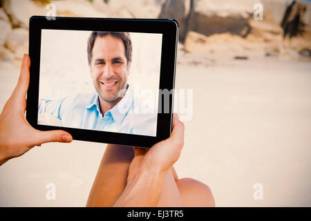Composite image of smiling handsome man sitting on the couch looking at camera Stock Photo