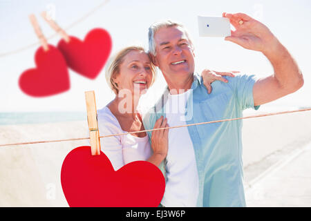 Composite image of happy senior couple posing for a selfie Stock Photo