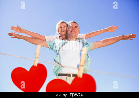 Composite image of happy senior man giving his partner a piggy back Stock Photo