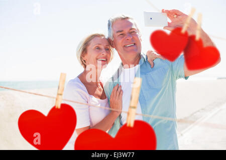 Composite image of happy senior couple posing for a selfie Stock Photo