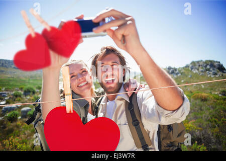 Composite image of hiking couple standing on mountain terrain taking a selfie Stock Photo
