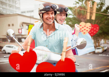 Composite image of hip young couple riding scooter with shopping bags Stock Photo