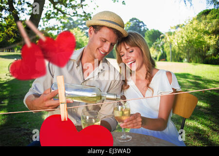 Composite image of cute couple drinking white wine together outside Stock Photo