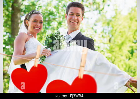 Composite image of groom carrying bride in garden Stock Photo