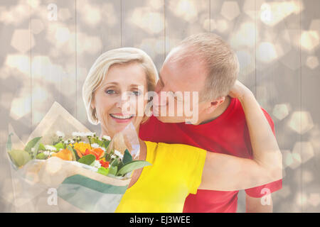 Composite image of mature man kissing his partner holding flowers Stock Photo