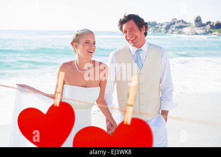 Composite image of newlyweds walking hand in hand and laughing Stock Photo