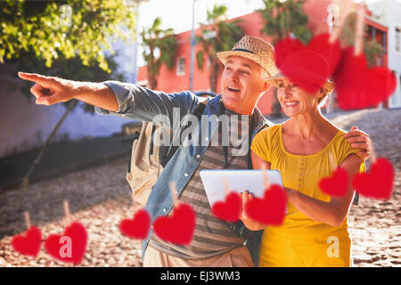 Composite image of happy tourist couple using tablet pc in the city Stock Photo