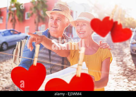 Composite image of happy tourist couple using map in the city Stock Photo