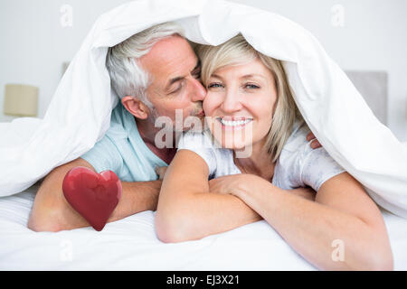 Composite image of closeup of mature man kissing womans cheek in bed Stock Photo