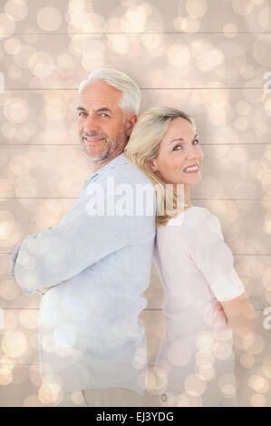 Composite image of smiling couple standing leaning backs together Stock Photo