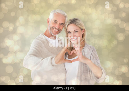 Composite image of happy couple forming heart shape with hands Stock Photo