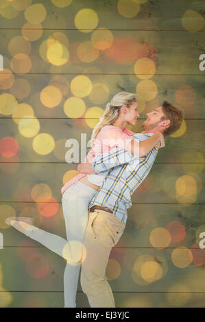 Composite image of handsome man picking up and hugging his girlfriend Stock Photo