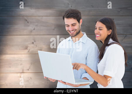 Composite image of attractive young couple holding their laptop Stock Photo