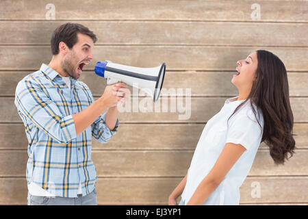 Composite image of angry man shouting at girlfriend through megaphone Stock Photo